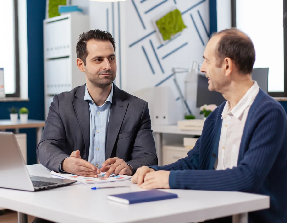 Berater im vertrauensvollen Gespräch mit einem zufriedenen Kunden im hellen Büro